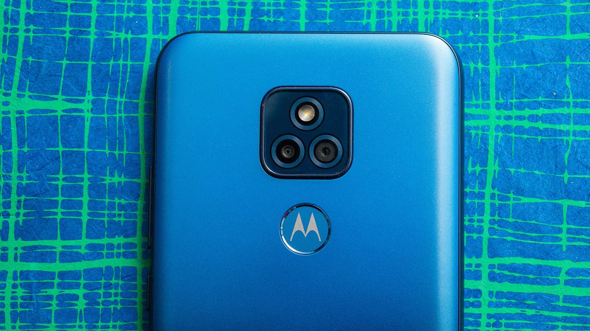 A blue Motorolo Moto G Play phone against a checkered green and blue background.