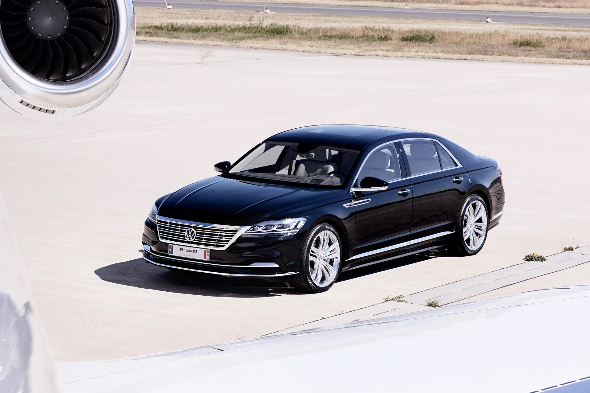 Front 3/4 view of a black Volkswagen Phaeton D2 prototype posed behind an airplane wing
