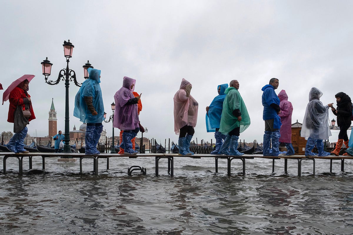 People walking on duckboards over floodwaters in Venice