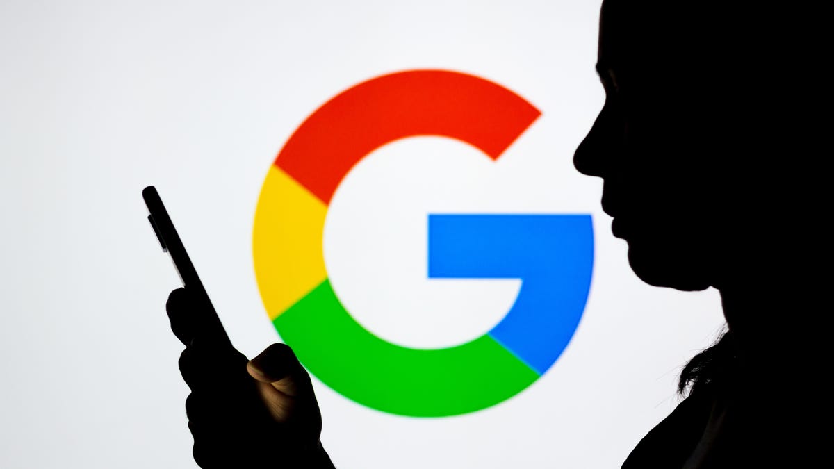 Silhouette of a person holding their phone over Google logo