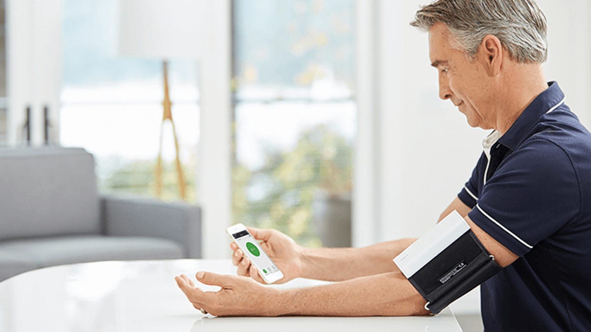 Man uses a wireless blood pressure monitor.
