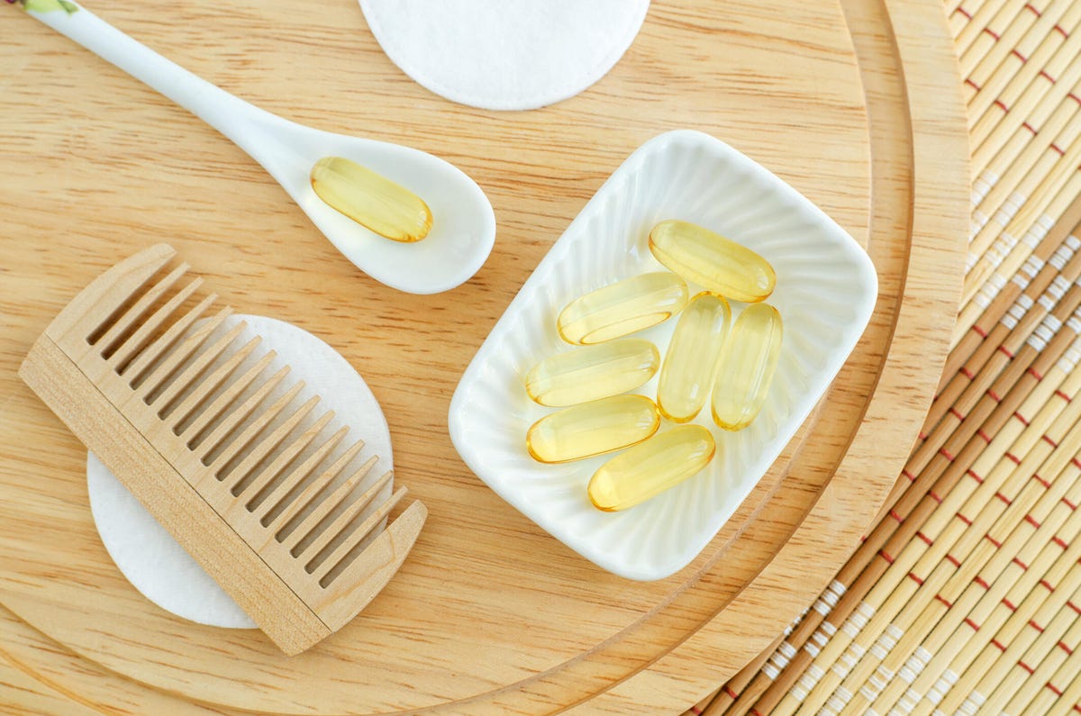 Table with a small white bowl of hair vitamins and a comb sitting next to it