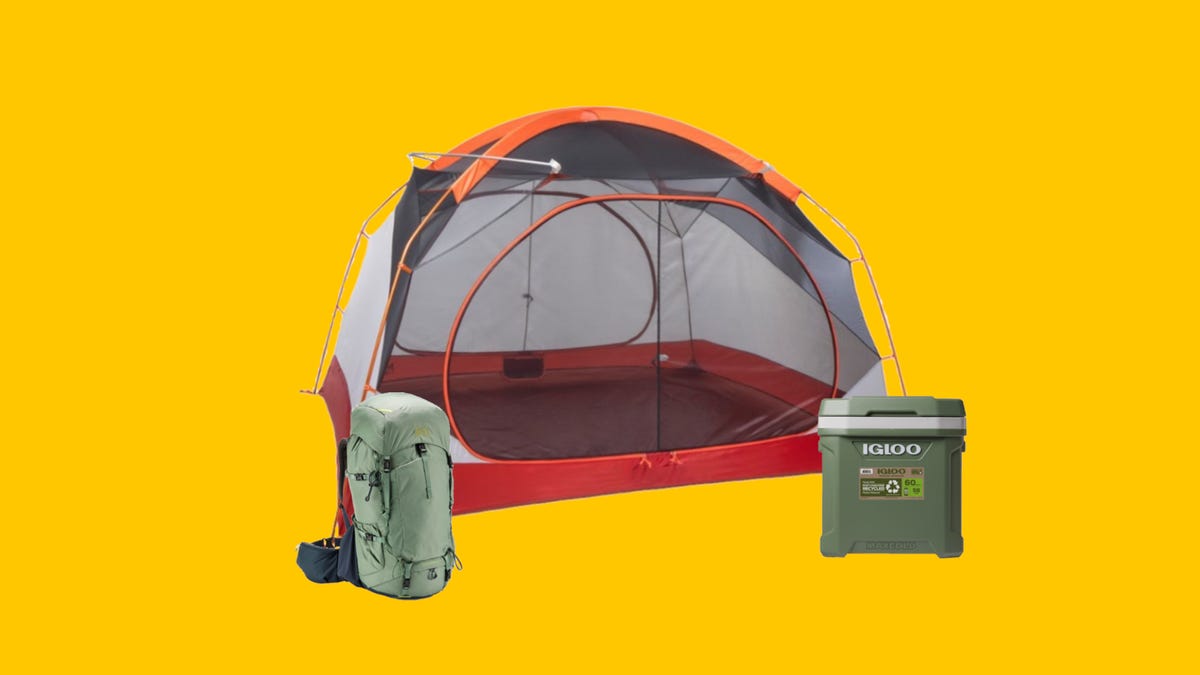 A gray and red tent next to a green hiking backpack and a green cooler on a yellow background