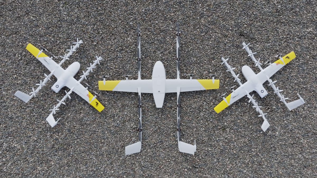A comparison showing a pair of Wing&apos;s smaller first-generation delivery drones to either side of a bigger new model that will join the Alphabet subsidiary&apos;s fleet. They all use the same basic design combining some propellers to lift the drone vertically with others that propel it horizontally.