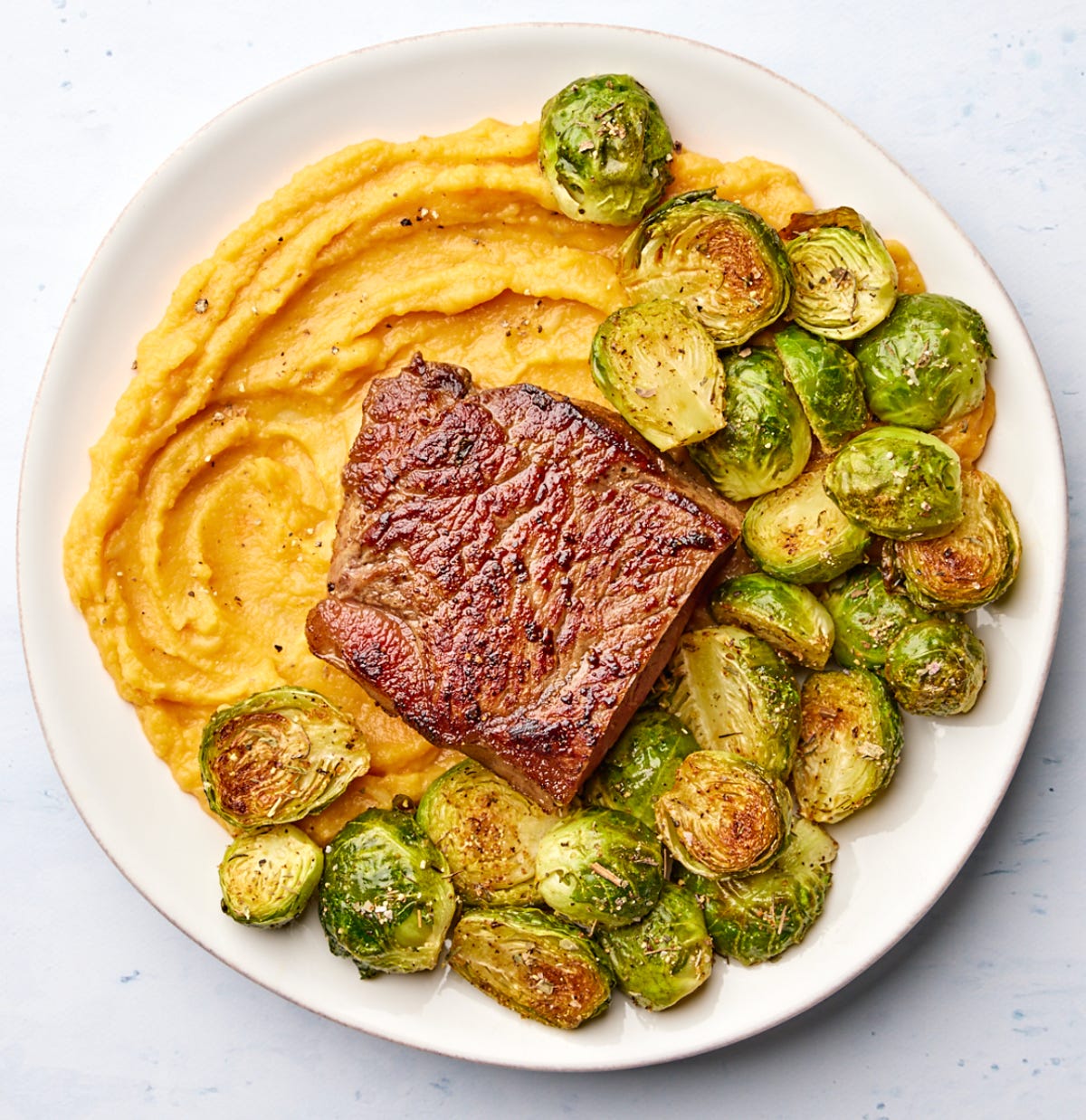 steak over mashed sweet potatoes with sprouts