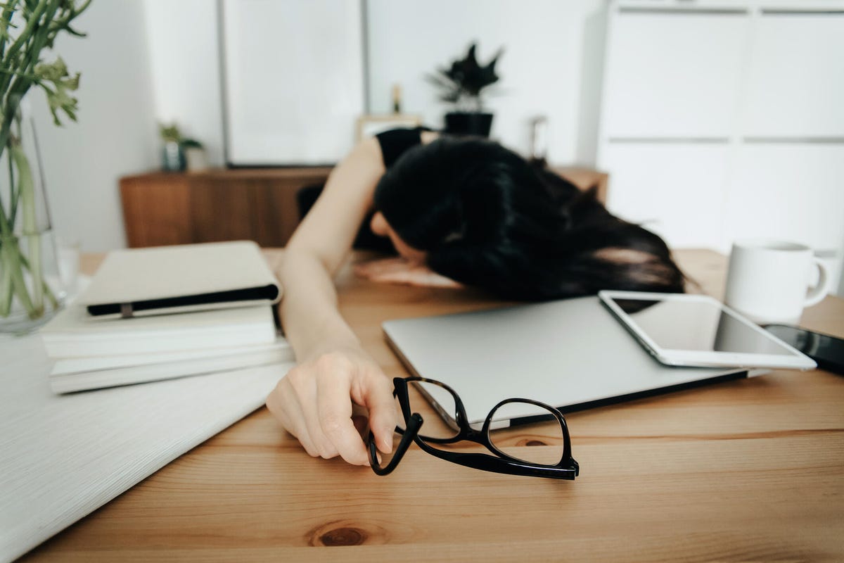 Frau gestresst am Schreibtisch schlafen