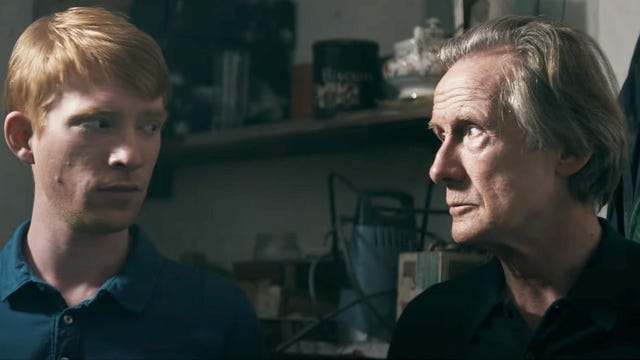 Domnhall Gleeson and Bill Nighy looking at each other indoors