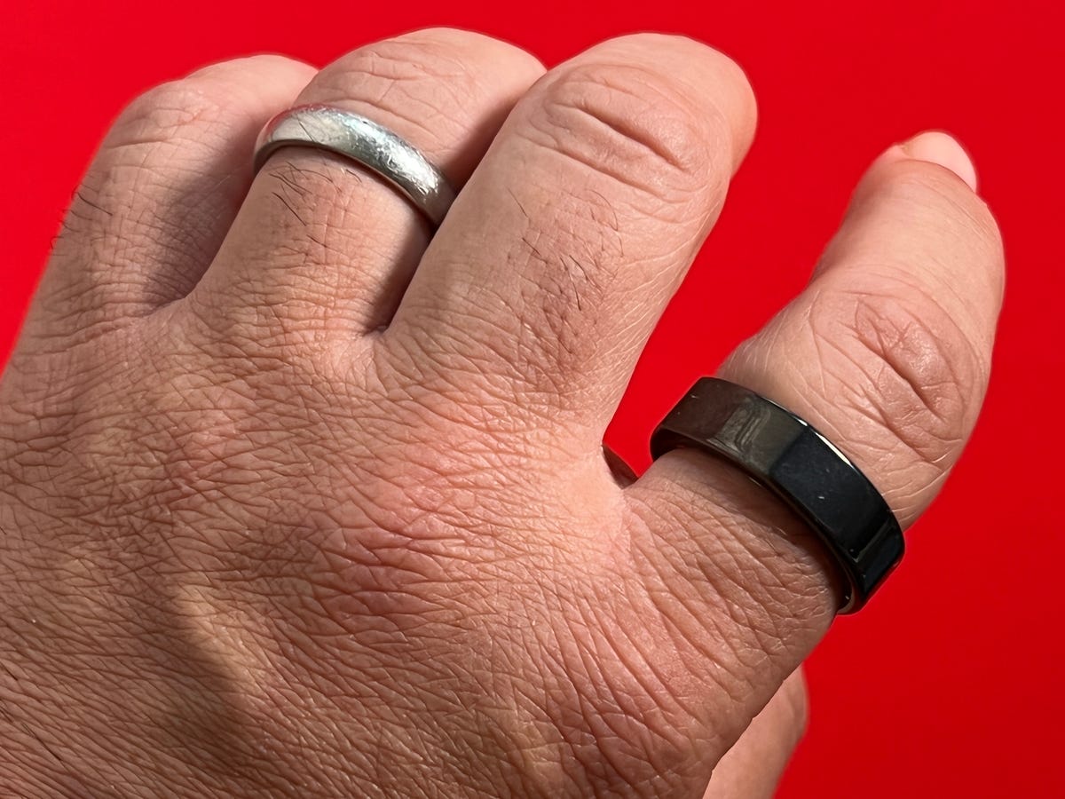 Usar uma aliança Oura 3 no dedo indicador, com uma aliança de casamento no dedo anelar.
