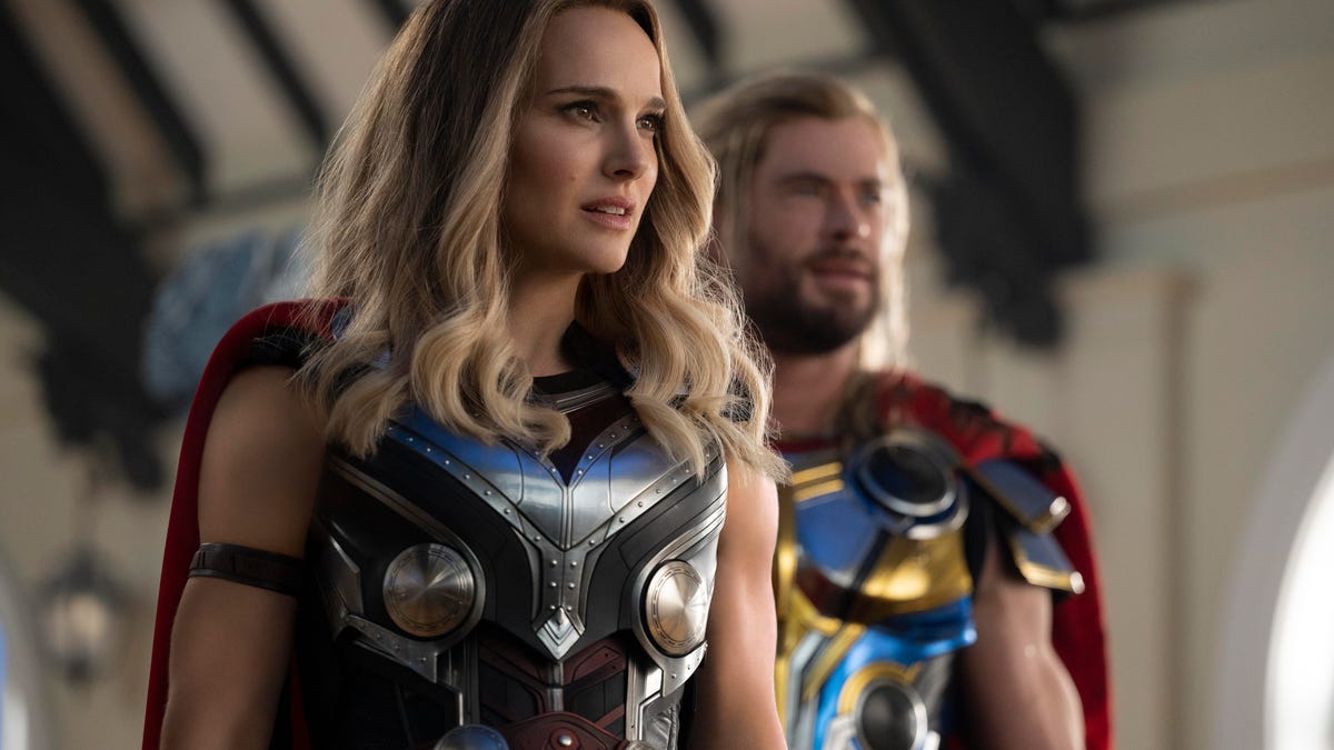 Jane Foster stands in the foreground with Thor in the background in Thor: Love and Thunder