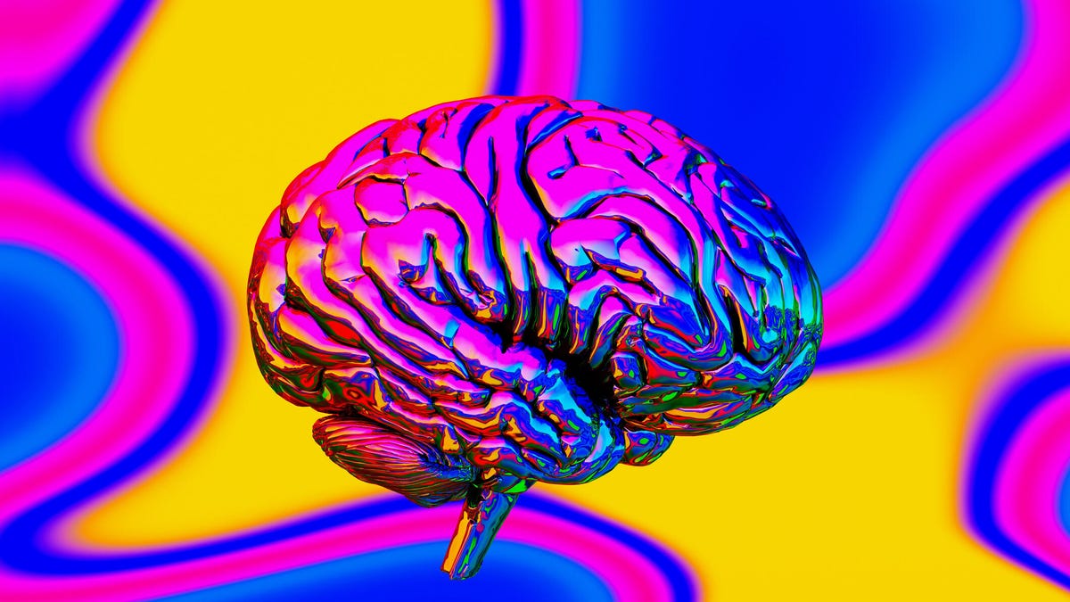 A metallic brain is shown against a pink, yellow and blue psychedelic background and reflects those colors as well.