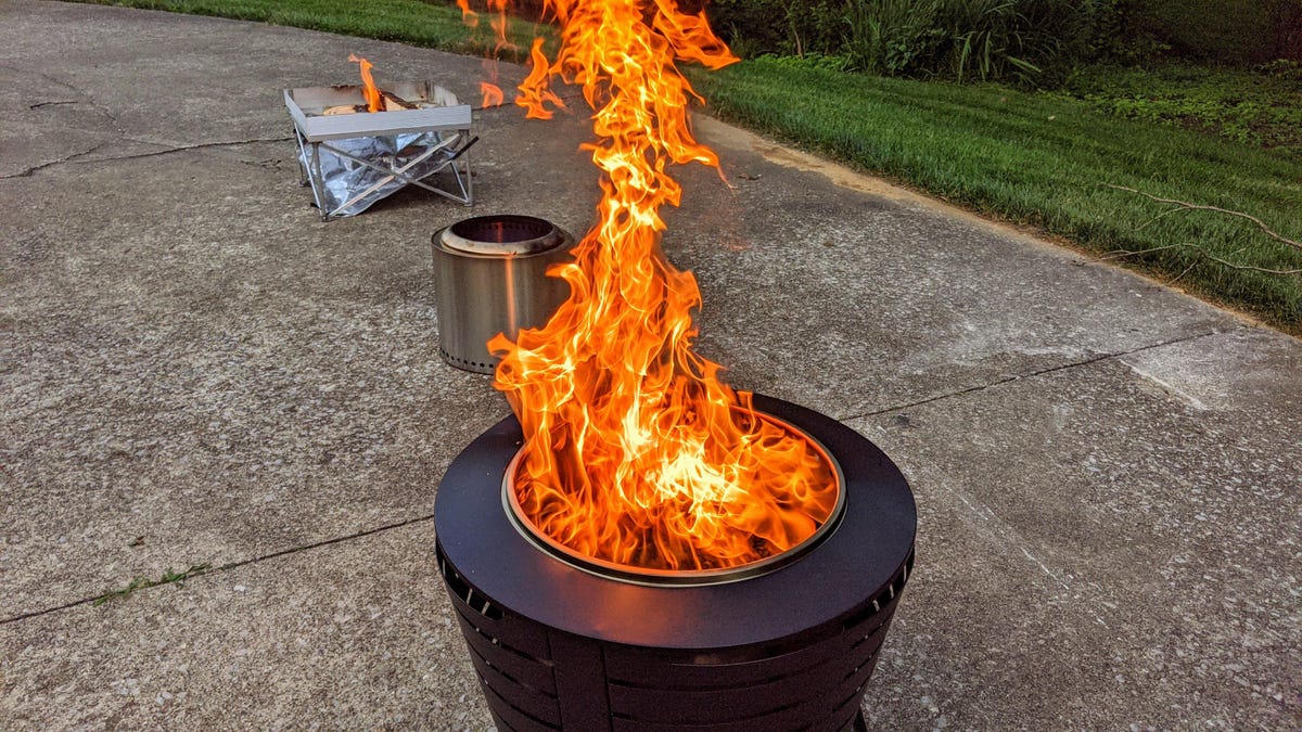 A black fire pit with a large flame, and two other fire pits in the background.
