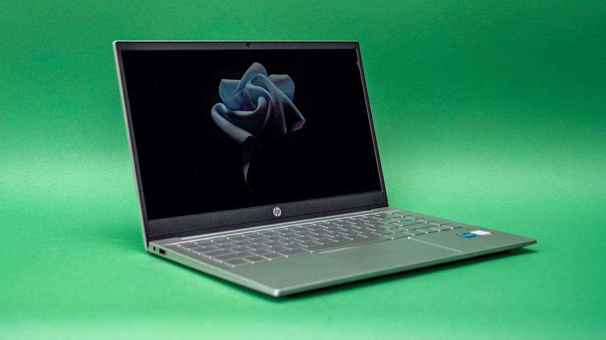 HP Pavilion 14 laptop open and facing to the right on a green background.