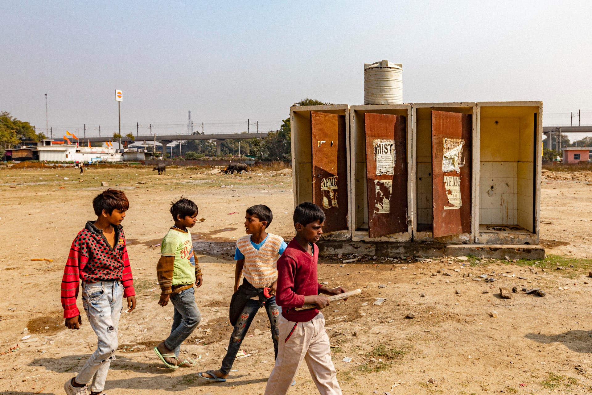 Four boys walk past one of the decrepit community toilets in the slums of Faridabad, India.