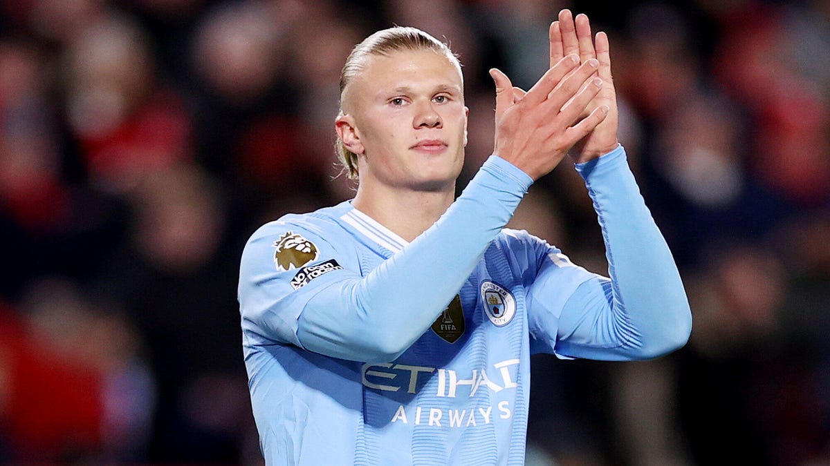 Erling Haaland of Manchester City with both hands raised applauding.
