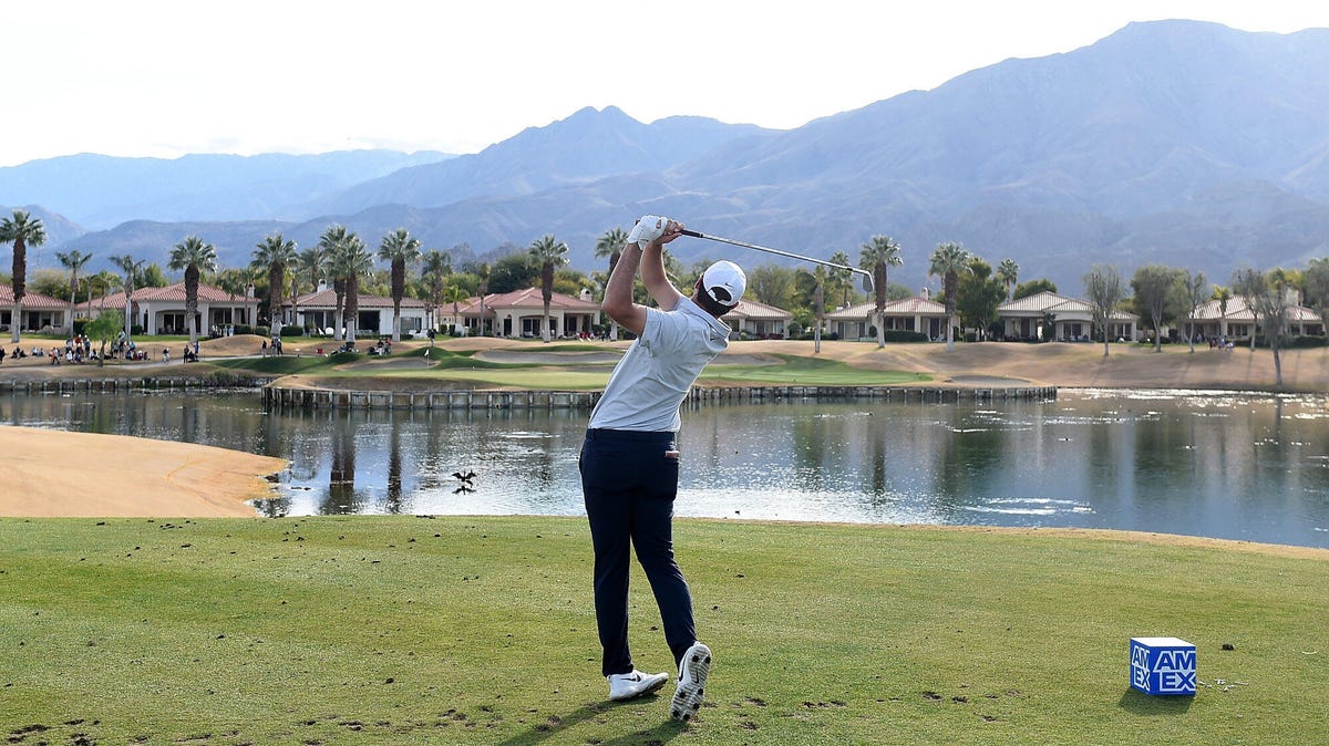 Golfer Scottie Scheffler pictured from behind as he tees off on the eighth hole of the PGA West course with a mountain vista in front of him.