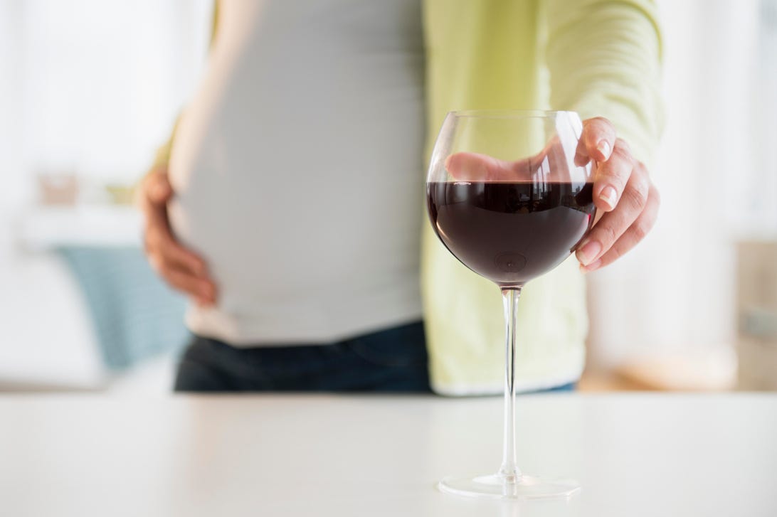 Pregnant woman with a hand on a wine glass