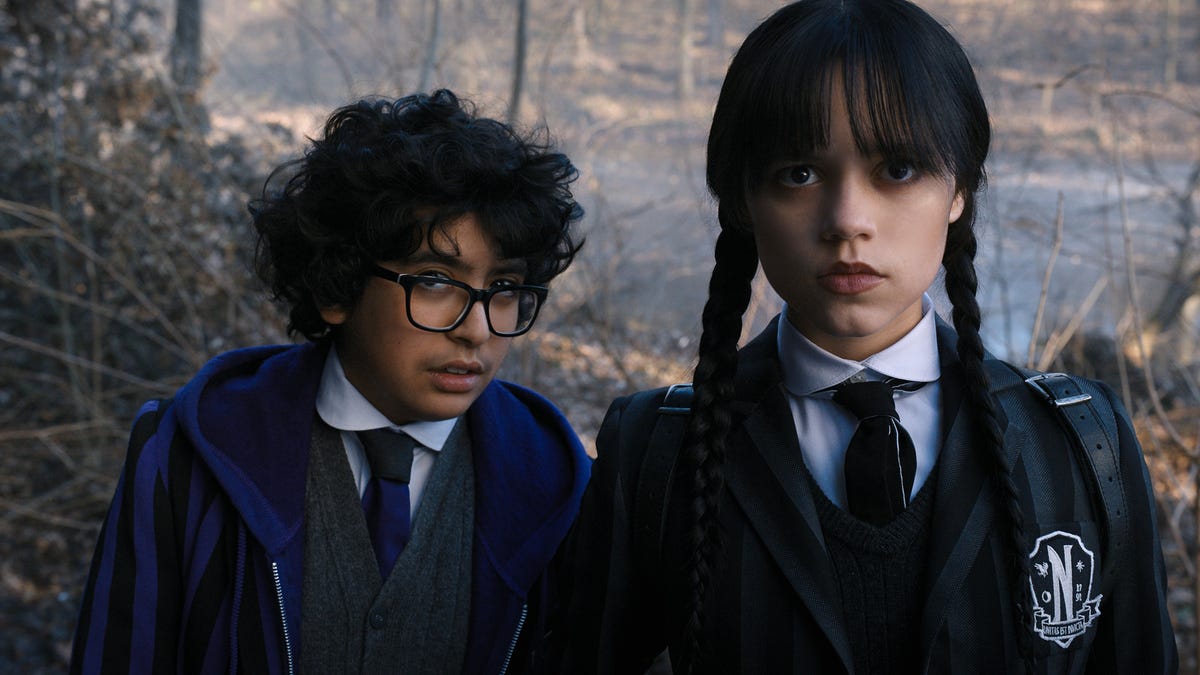 Two students including Wednesday Addams standing out in the woods