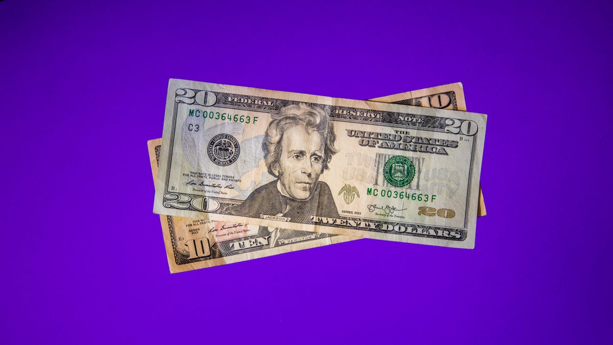 A stack of $20 and $10 bills on a purple background