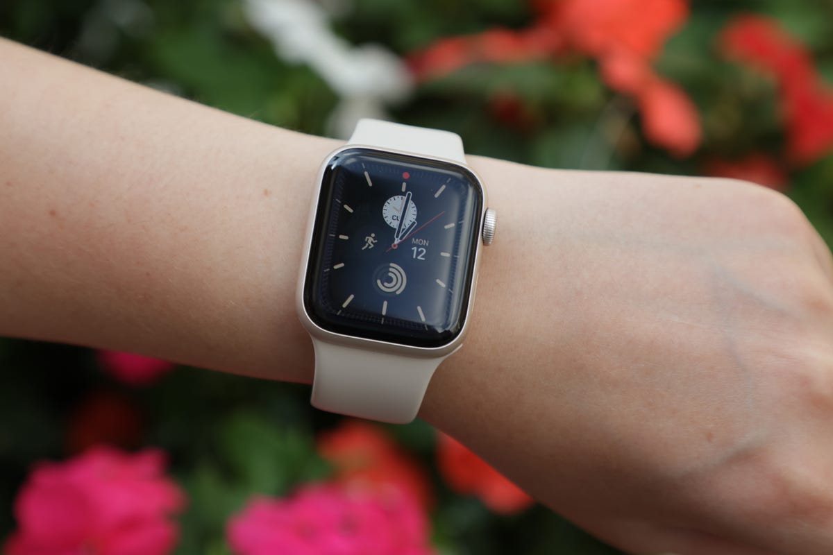 The 2022 Apple Watch SE being worn with flowers in the background