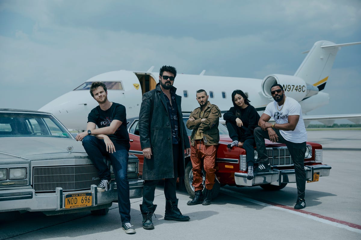 Butcher and The Boys look cool lounging on cars in front of a private jet.