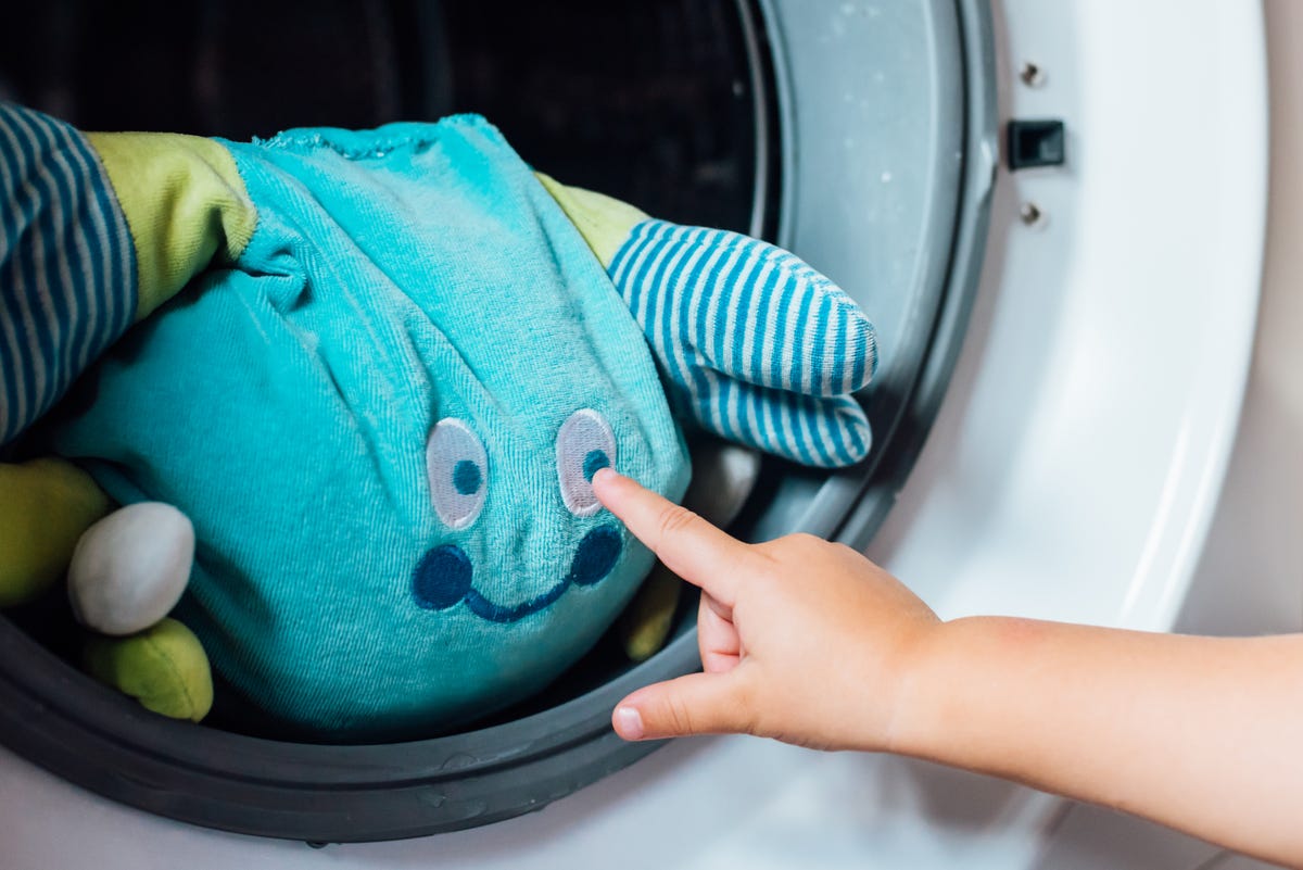 A child's hand poking a toy in a washing machine