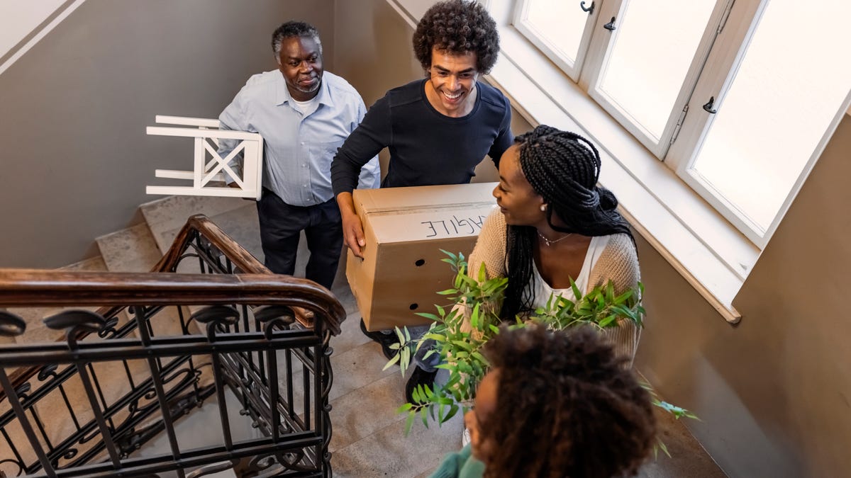 members of a family move boxes and belongings up a staircase