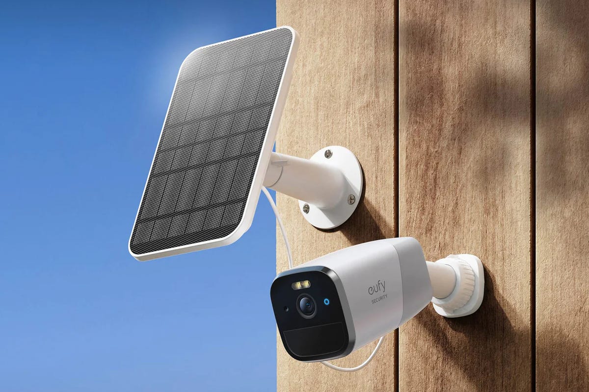 A Eufy cam mounted outside on a wood board wall with the Eufy solar panel installed above it facing the sun.