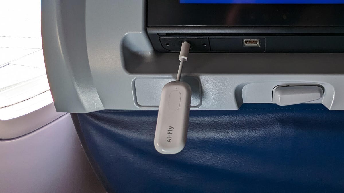 The Airfly Pro plugged into the back of an aircraft seat.
