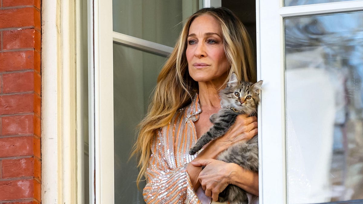 Sarah Jessica Parker stands on a balcony and holds a kitten