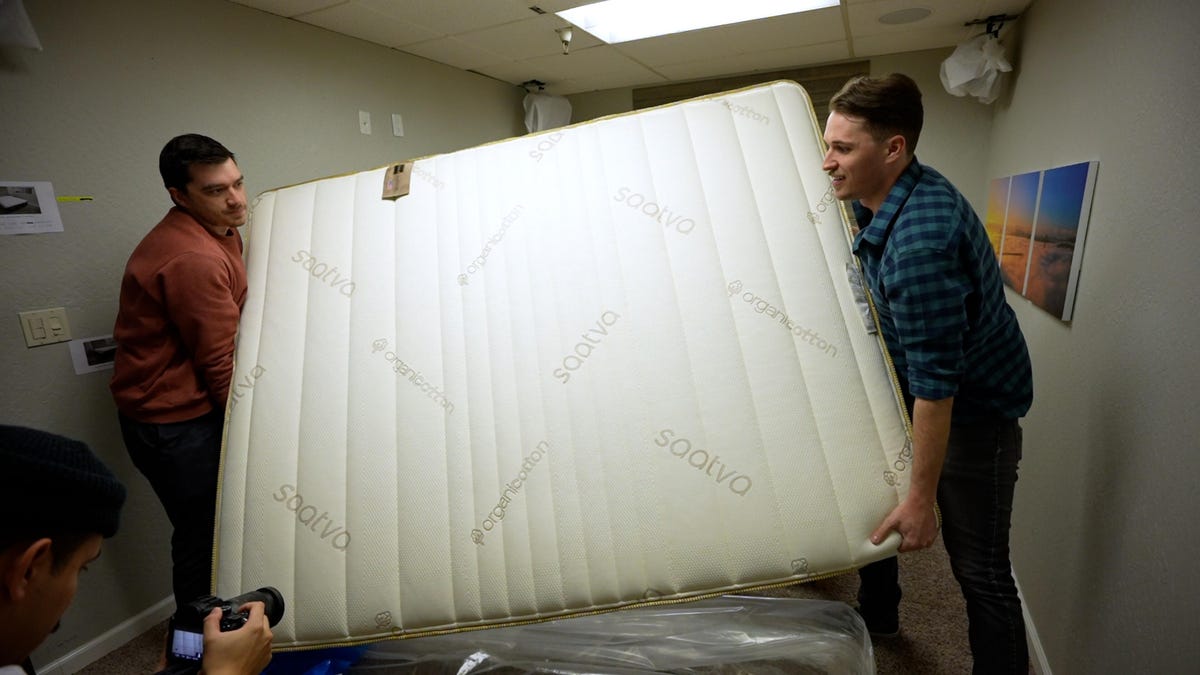 Two CNET Video producers moving a mattress onto a bedframe