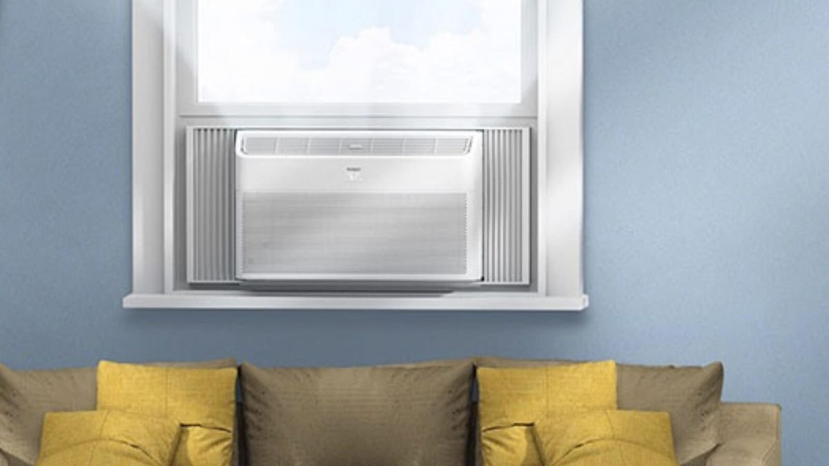 A window air conditioning unit is installed above a couch.