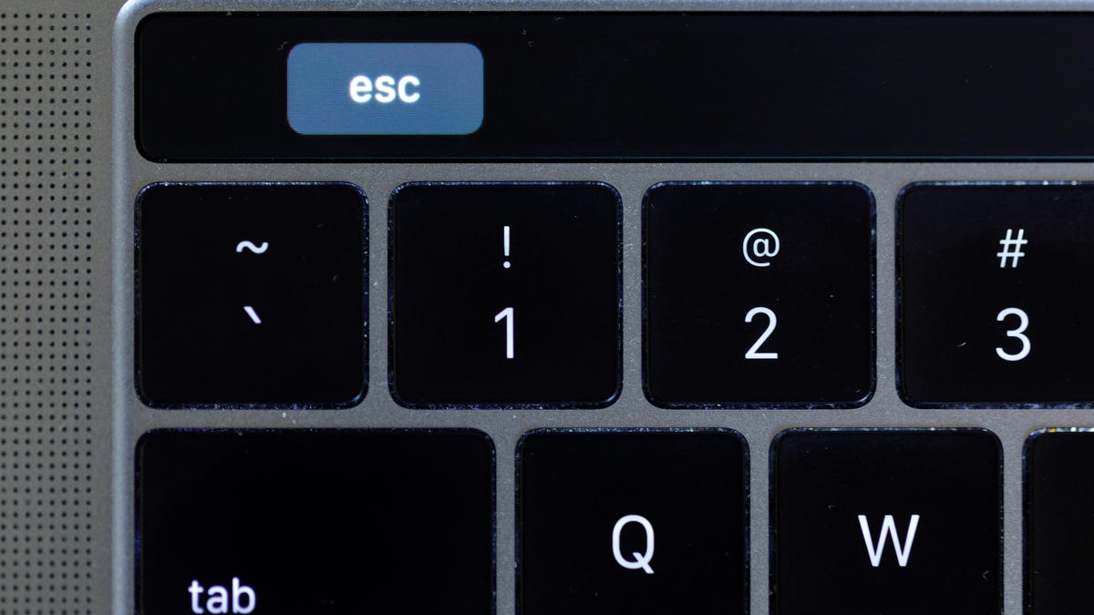 The MacBook Pro Touch Bar's virtual escape key is inset to the right.