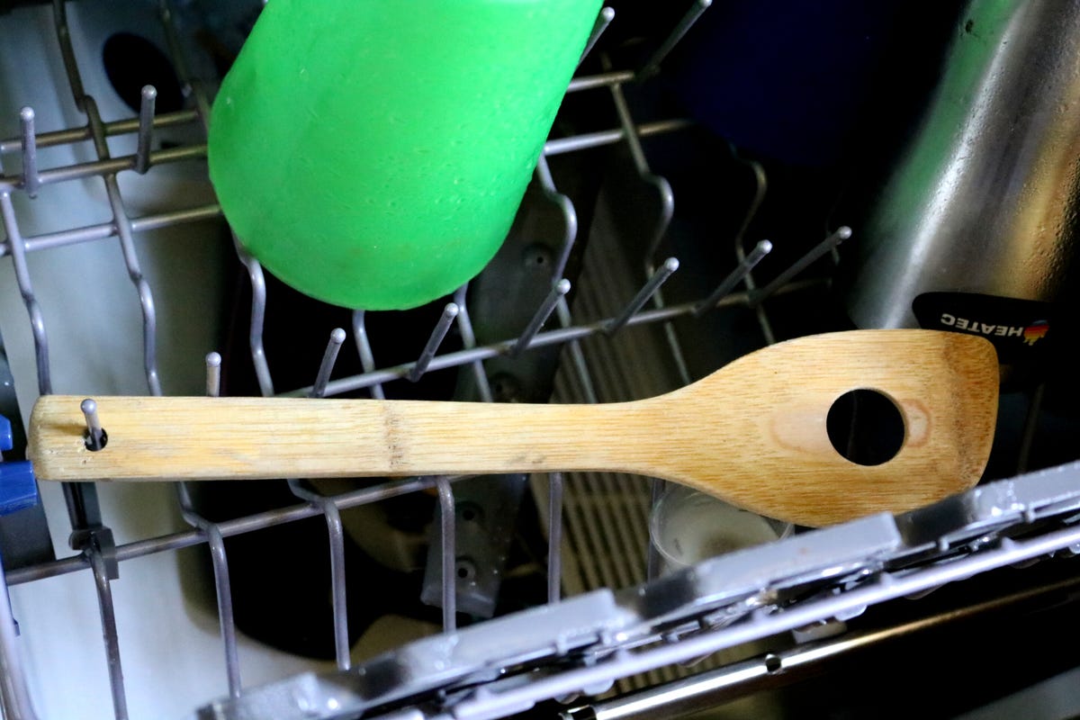A spatula in the dishwasher with a tine through a hole in the handle