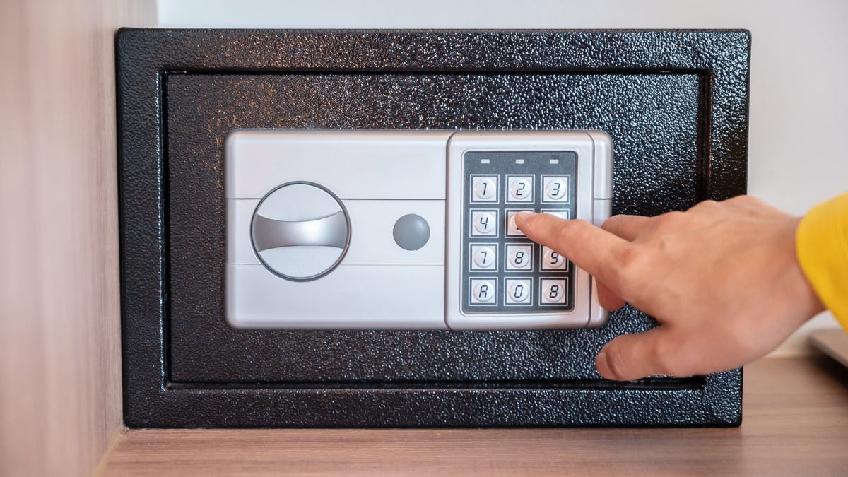 a person enters the code on a keypad on a small safe