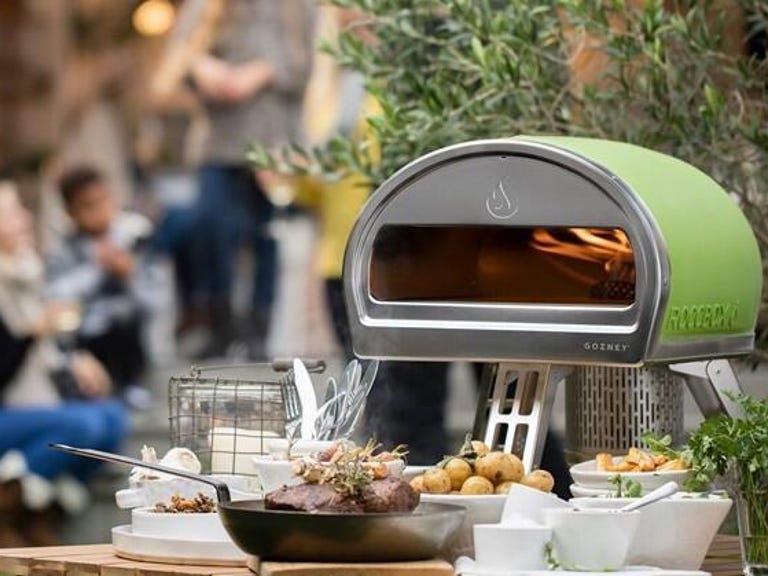 green pizza oven sitting on outdoor table