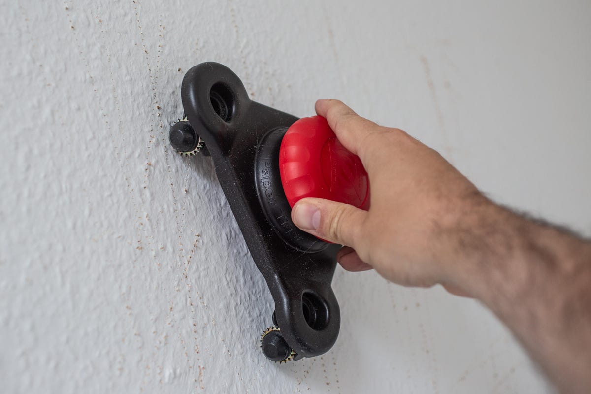 Image showing a hand holding a tool against a wall