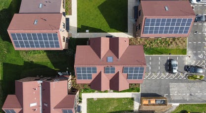 Aerial view of solar panels on homes with red roofs.