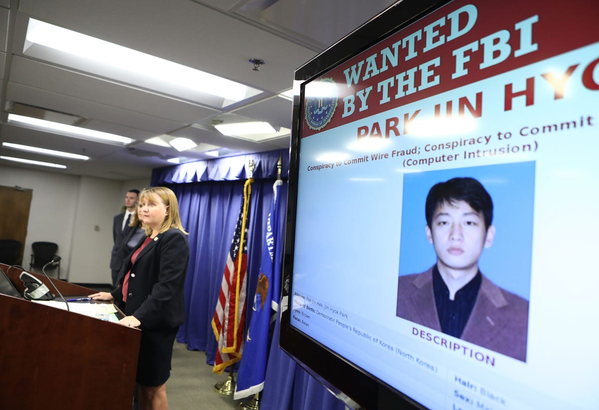 A large TV screen at a briefing by a US Attorney shows a North Korean man suspected of participating in cyberattacks.