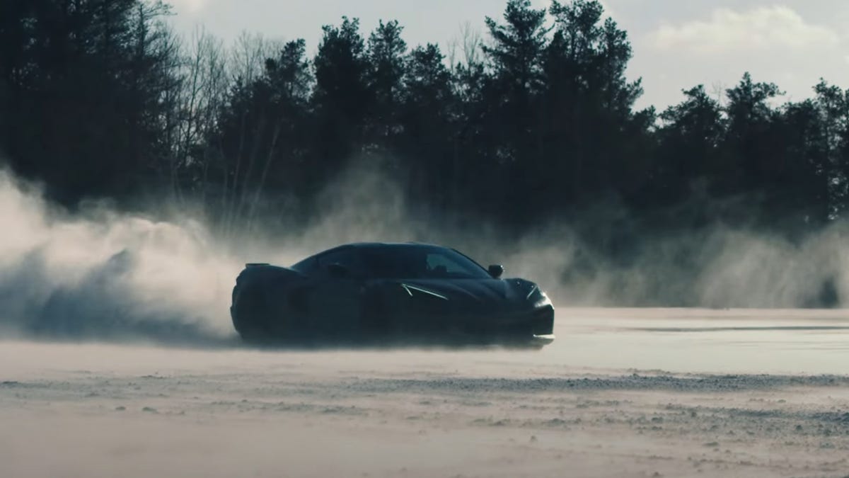 a dark Chevrolet Corvette kicks up dust on salt flats
