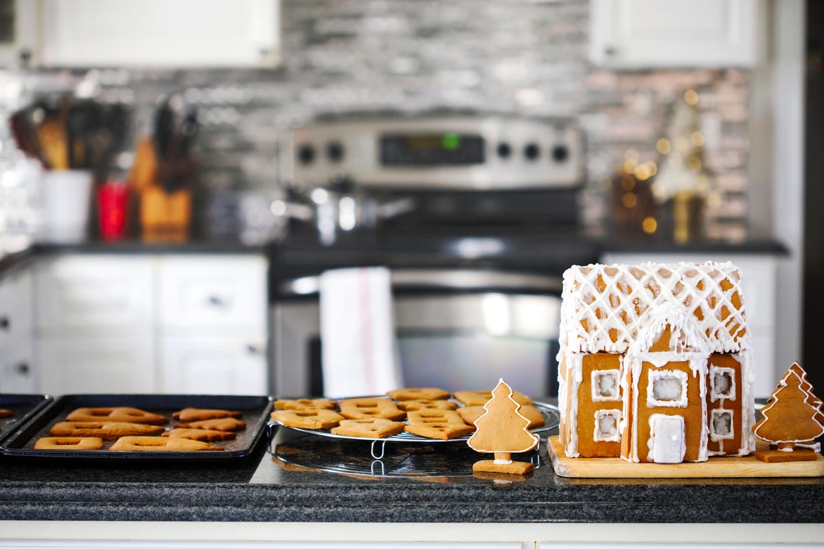 Gingerbread house and cookies on a kitchen counter.