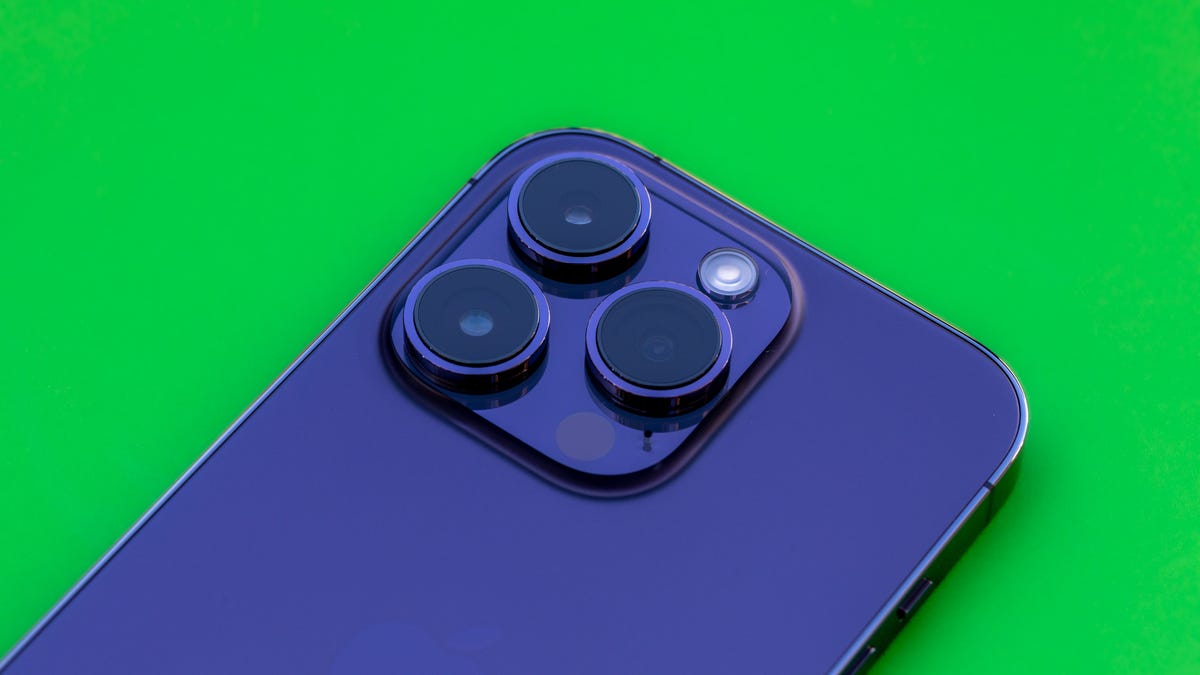 The three rear cameras of a deep purple iPhone 14 Pro point upward