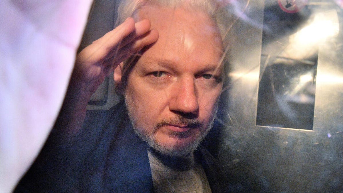 WikiLeaks founder Julian Assange gestures from the window of a prison van as he's driven out of a London court on May 1, 2019, after being sentenced to 50 weeks in prison for breaching his bail conditions in 2012.