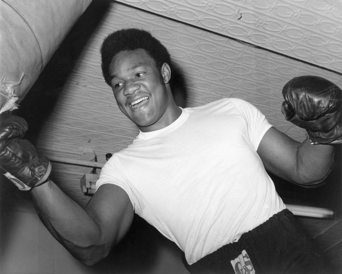 Boxer George Foreman. Shot taken from a low angle shows Foreman striking a workout bag. Undated photograph.