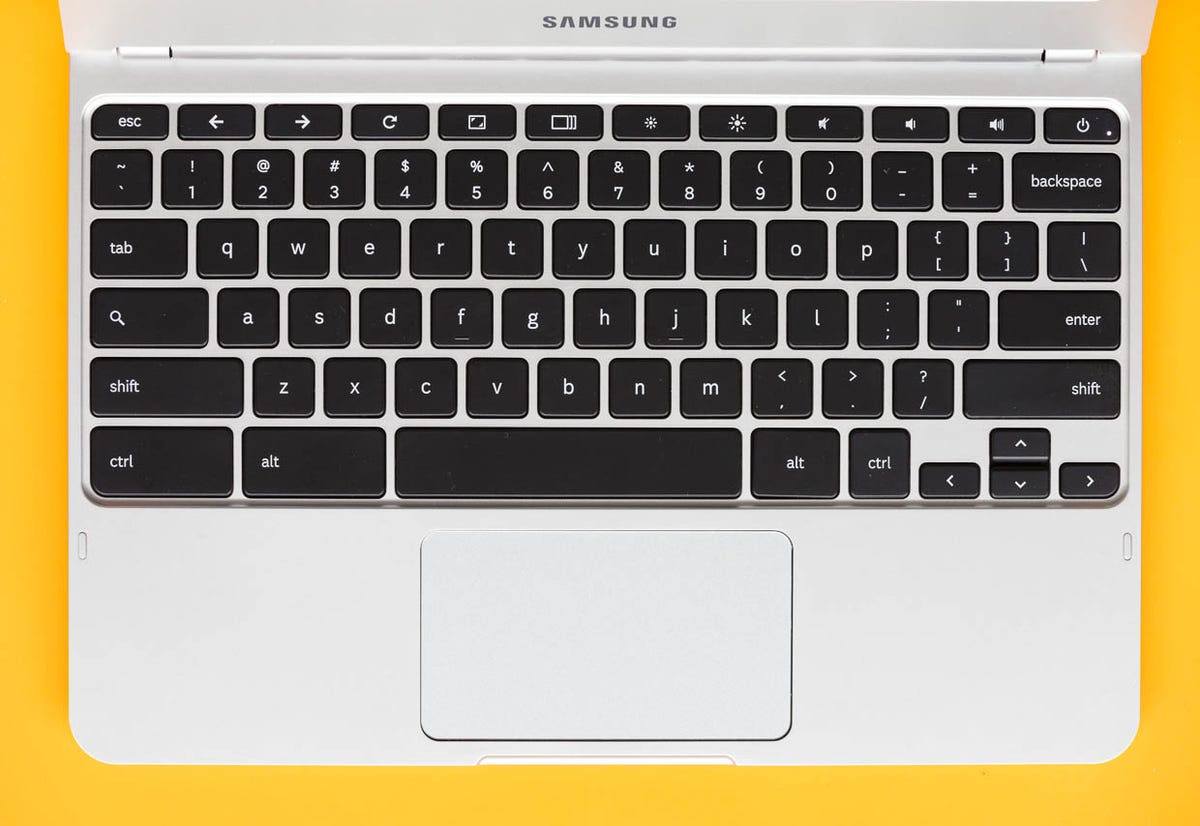 The Samsung Chromebook has a non-backlit chiclet keyboard with controls for screen brightness, volume, window switching, and browser navigation along the top. A wide trackpad supports multitouch gestures.