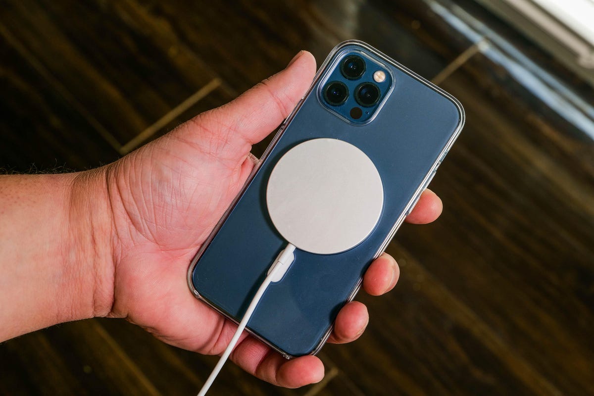 A MagSafe Charger on a phone in a person's hand
