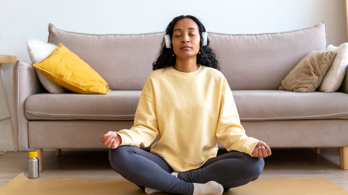 Woman sitting on a yoga mat meditating and focusing on breath.
