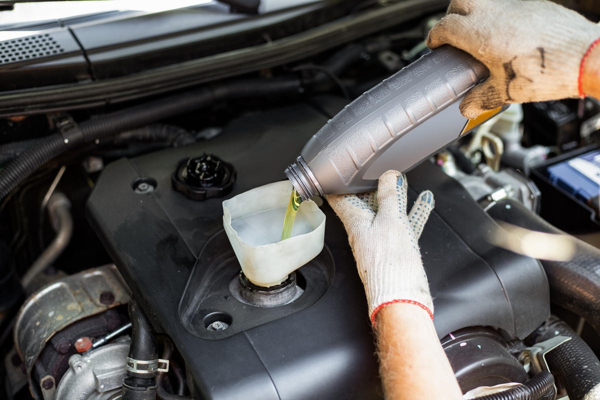 A person pouring motor oil into their engine