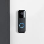 Blink's video doorbell mounted on a white wall.