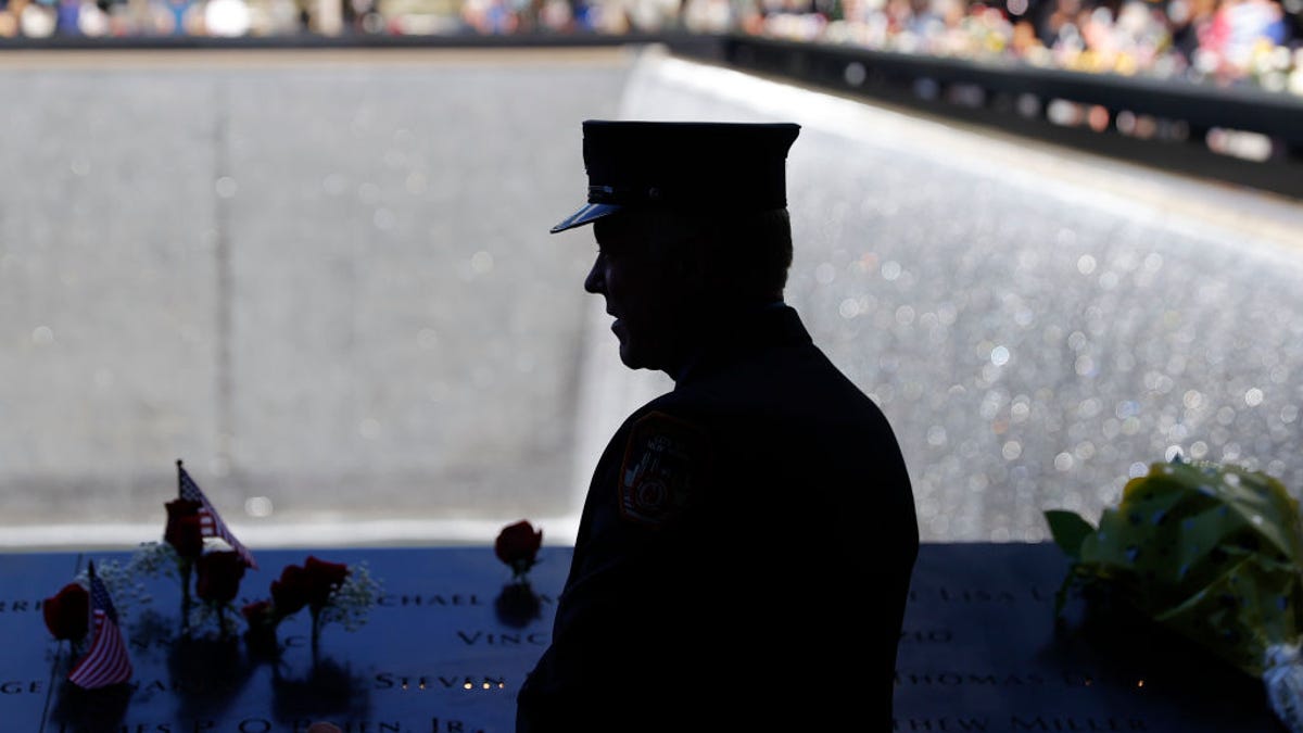 A member of the Fire Department of New York stands by the north reflecting pool at the National September 11 Memorial & Museum in Manhattan during a ceremony commemorating the 20th anniversary of the Sept. 11 terrorist attacks.