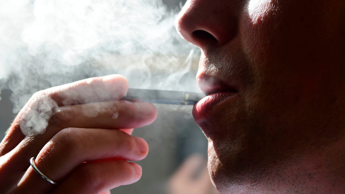 A man exhaling a cloud of smoke from an electronic cigarette.